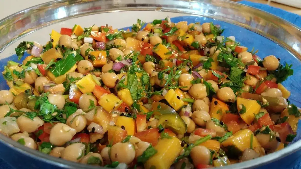 Ensalada de legumbres vibrante con garbanzos, pimientos de colores, cebolla morada y cilantro fresco.