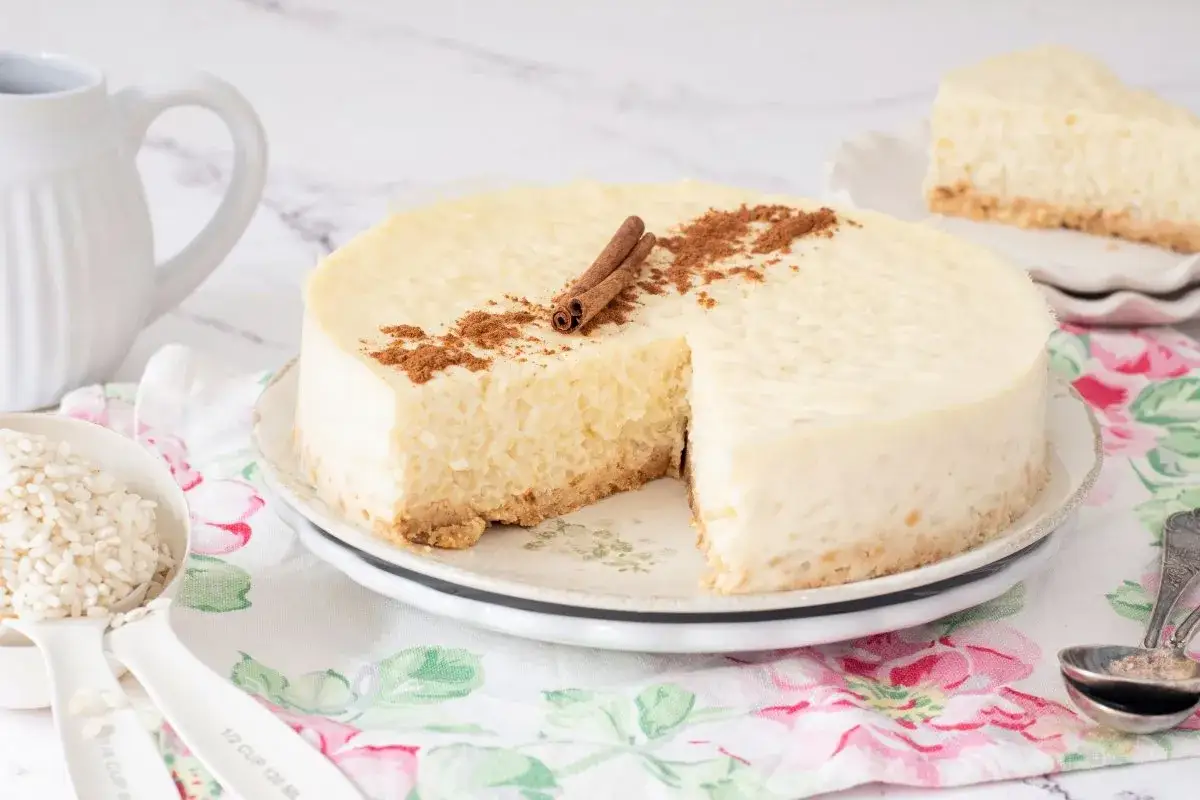 Tarta de arroz cremosa, decorada con canela en rama y espolvoreada, lista para disfrutar.