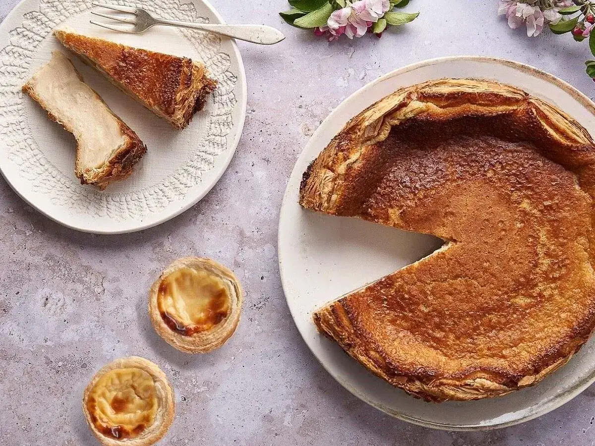 Un pastel de arroz dorado, dos porciones en un plato y dos pastelitos de nata.