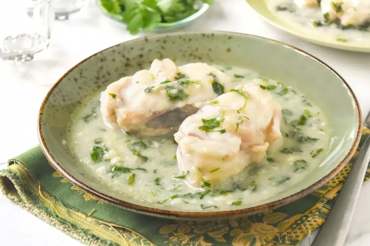 Dos trozos de rape en una cremosa salsa verde, adornados con perejil fresco. Un plato delicioso y reconfortante.
