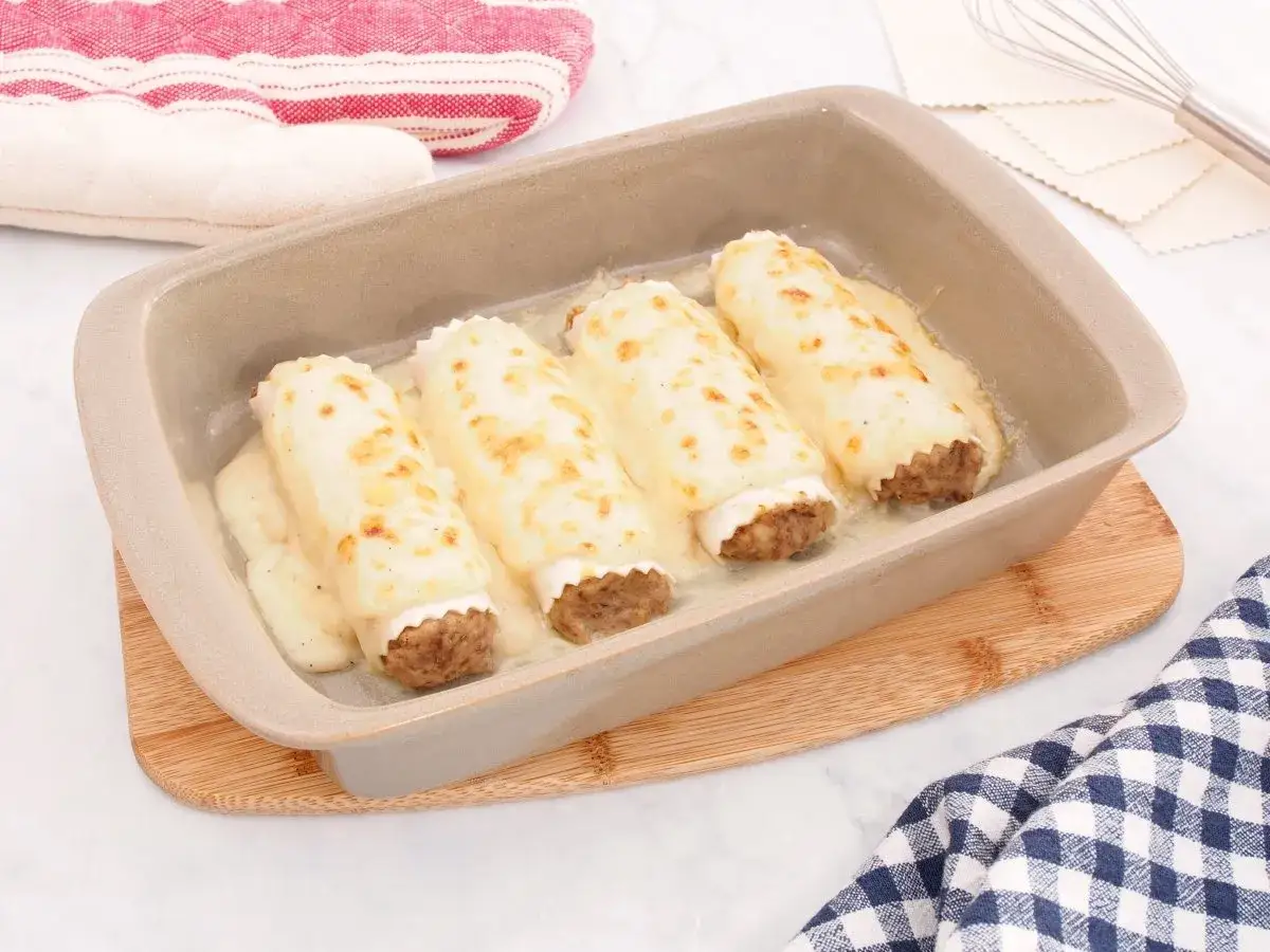 Canelones de carne, receta de la abuela, horneados con queso gratinado en una bandeja de cerámica.
