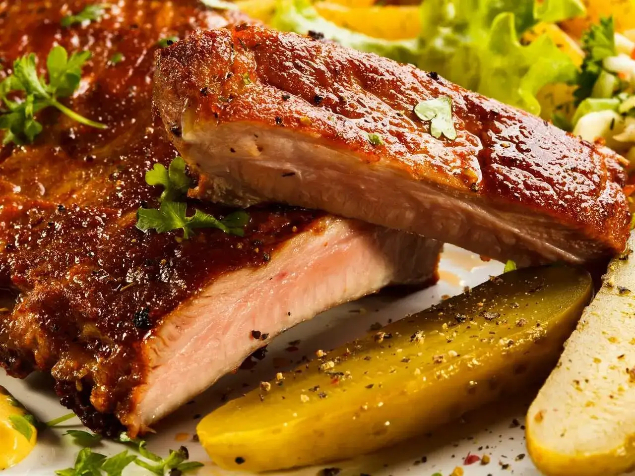 Costillas al horno con patatas, jugosas y doradas, con perejil fresco y un toque de pimienta.