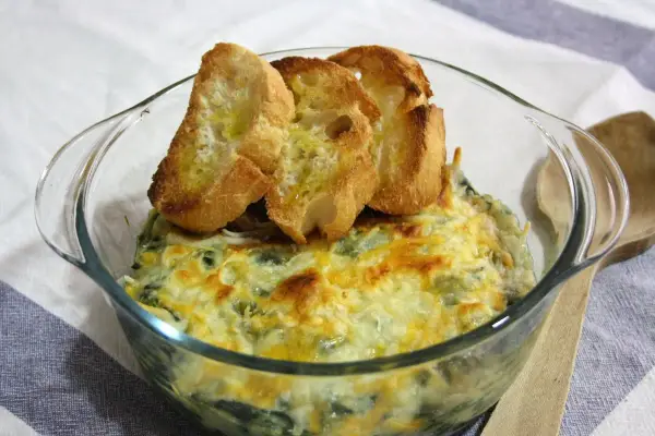 Delicioso plato de espinacas con bechamel gratinado, coronado con tostaditas de pan.