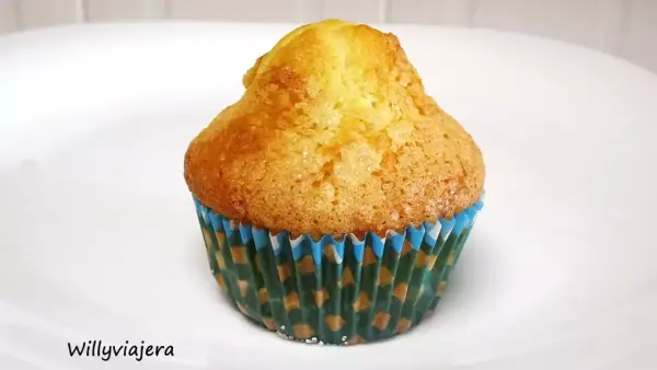 Una magdalena casera, dorada y esponjosa, en su envoltorio de papel con motivos verdes y azules. ¡Perfecta para el desayuno!